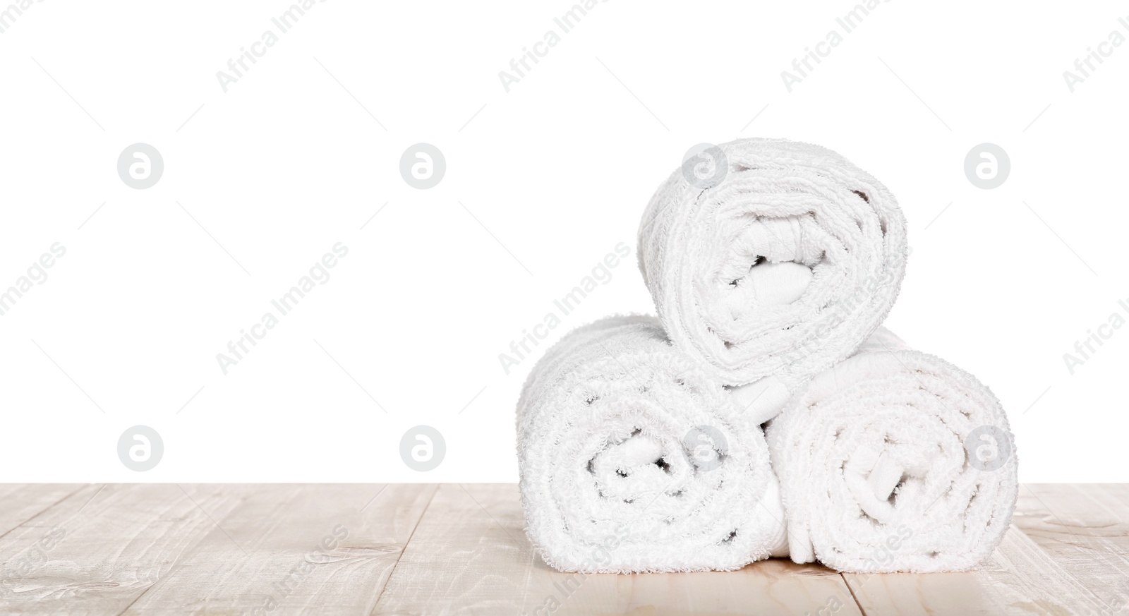 Photo of Soft terry towels on wooden table against white background, space for text