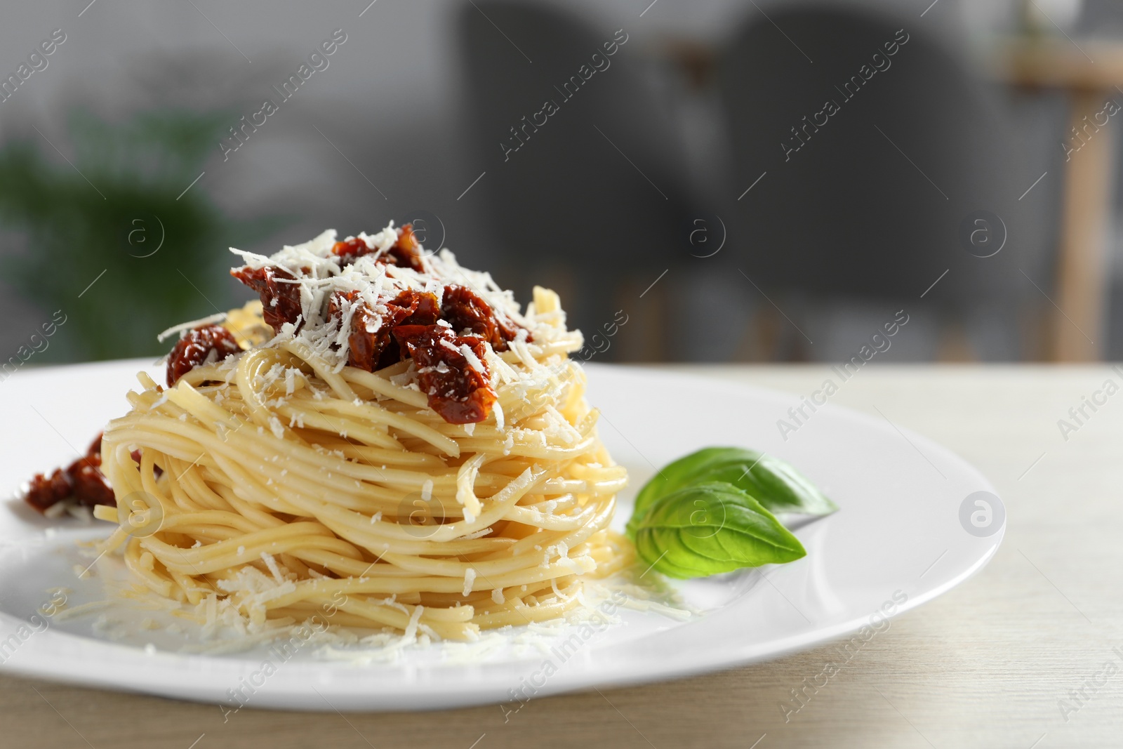 Photo of Tasty spaghetti with sun-dried tomatoes and parmesan cheese on wooden table in restaurant, closeup. Exquisite presentation of pasta dish