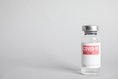 Vial with coronavirus vaccine on light background, space for text