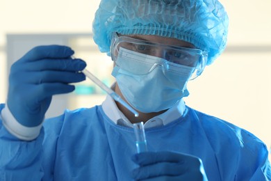 Photo of Scientist dripping sample into test tube in laboratory, closeup. Medical research