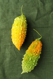 Fresh bitter melons on dark green cloth, flat lay