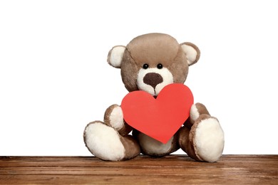 Photo of Cute teddy bear with red heart on wooden table against white background