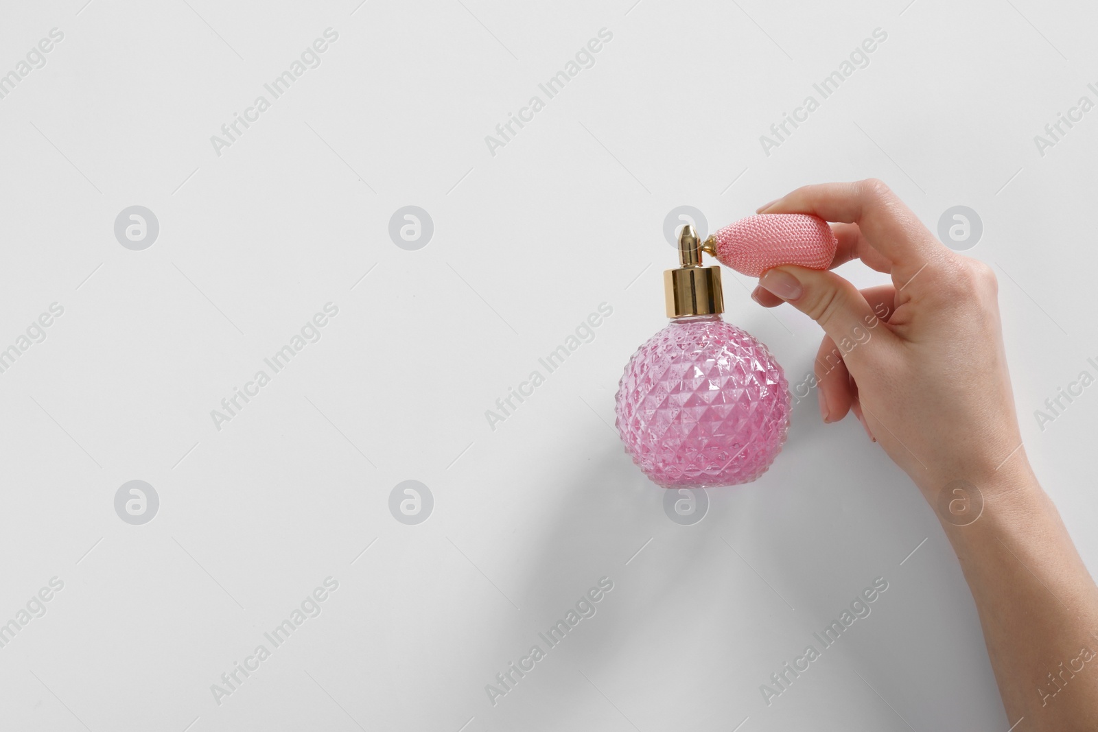 Photo of Woman with bottle of perfume on white background, top view. Space for text