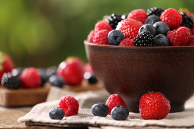 Bowl and different fresh ripe berries on table outdoors, closeup