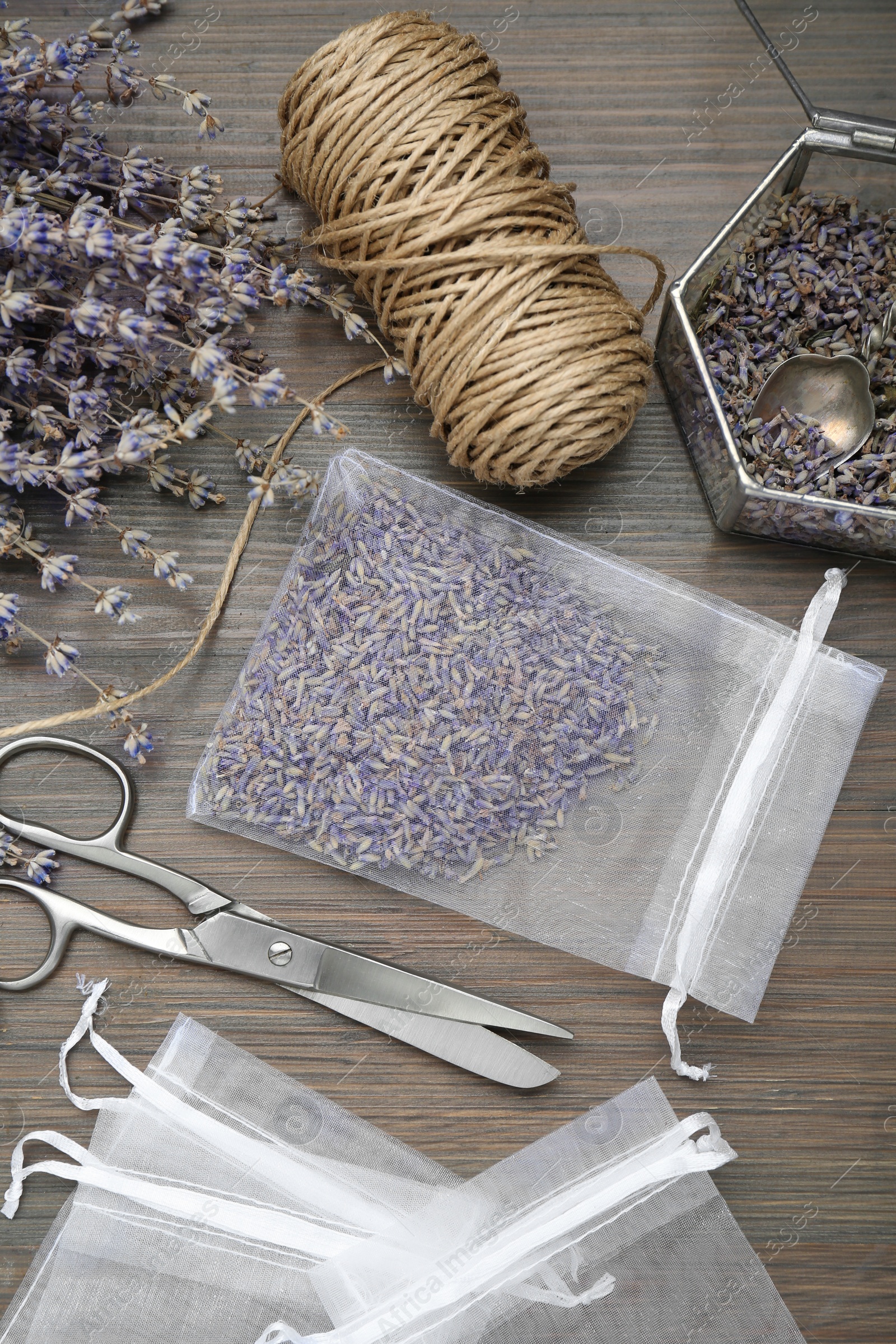 Photo of Scented sachet with dried lavender flowers, scissors and twine on wooden table, flat lay