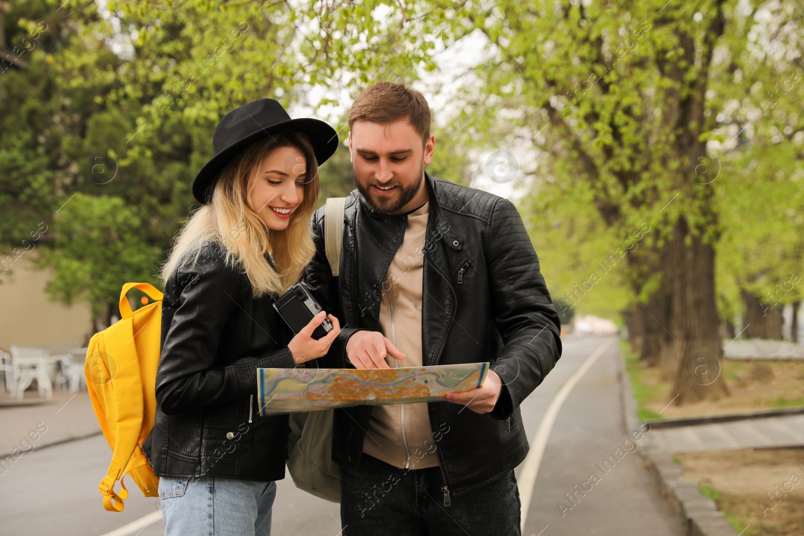 Photo of Couple of tourists with map planning trip on city street