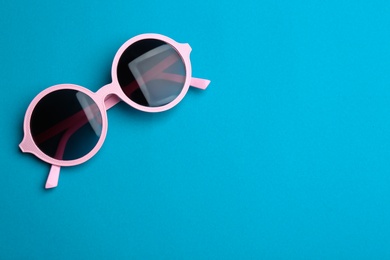 Photo of Stylish sunglasses on blue background, top view with space for text. Fashionable accessory