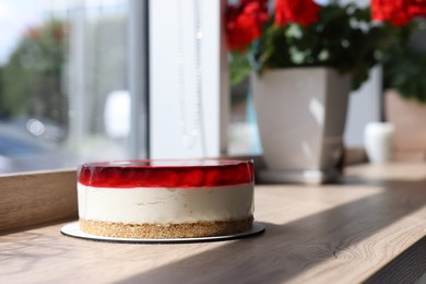 Photo of Delicious cheesecake with jelly and strawberries on wooden table. Space for text