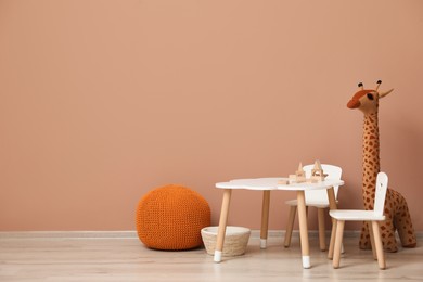 Photo of Cute child room interior with furniture and toys near pink wall. Space for text