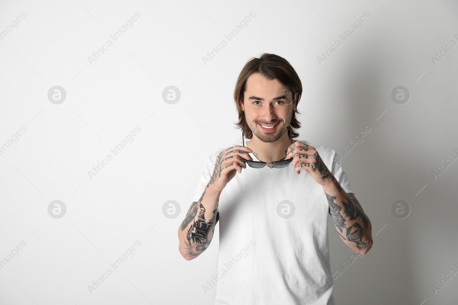 Photo of Young man with tattoos on arms against white background