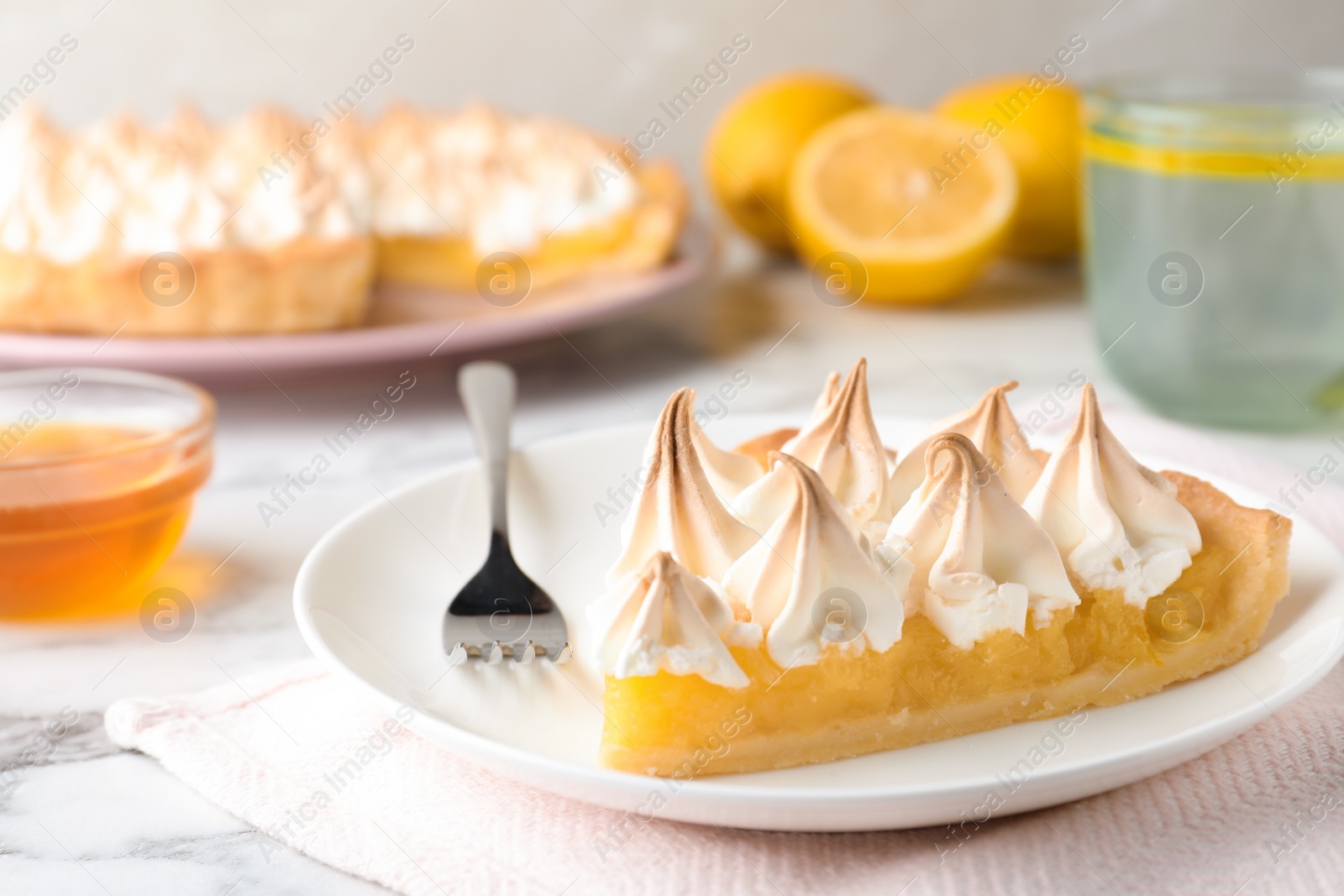 Photo of Piece of delicious lemon meringue pie served on white marble table, closeup