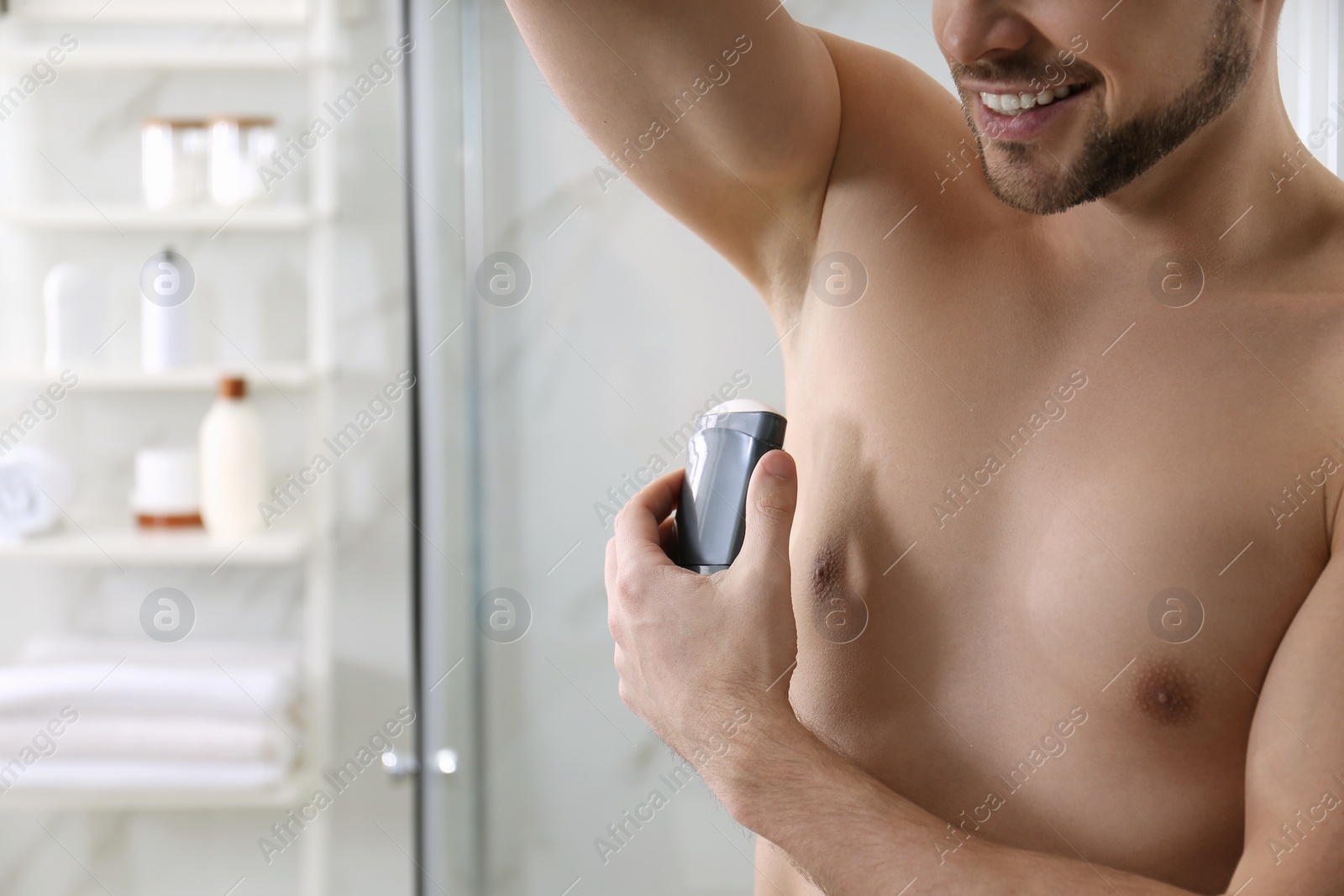 Photo of Man applying deodorant in bathroom, closeup. Space for text