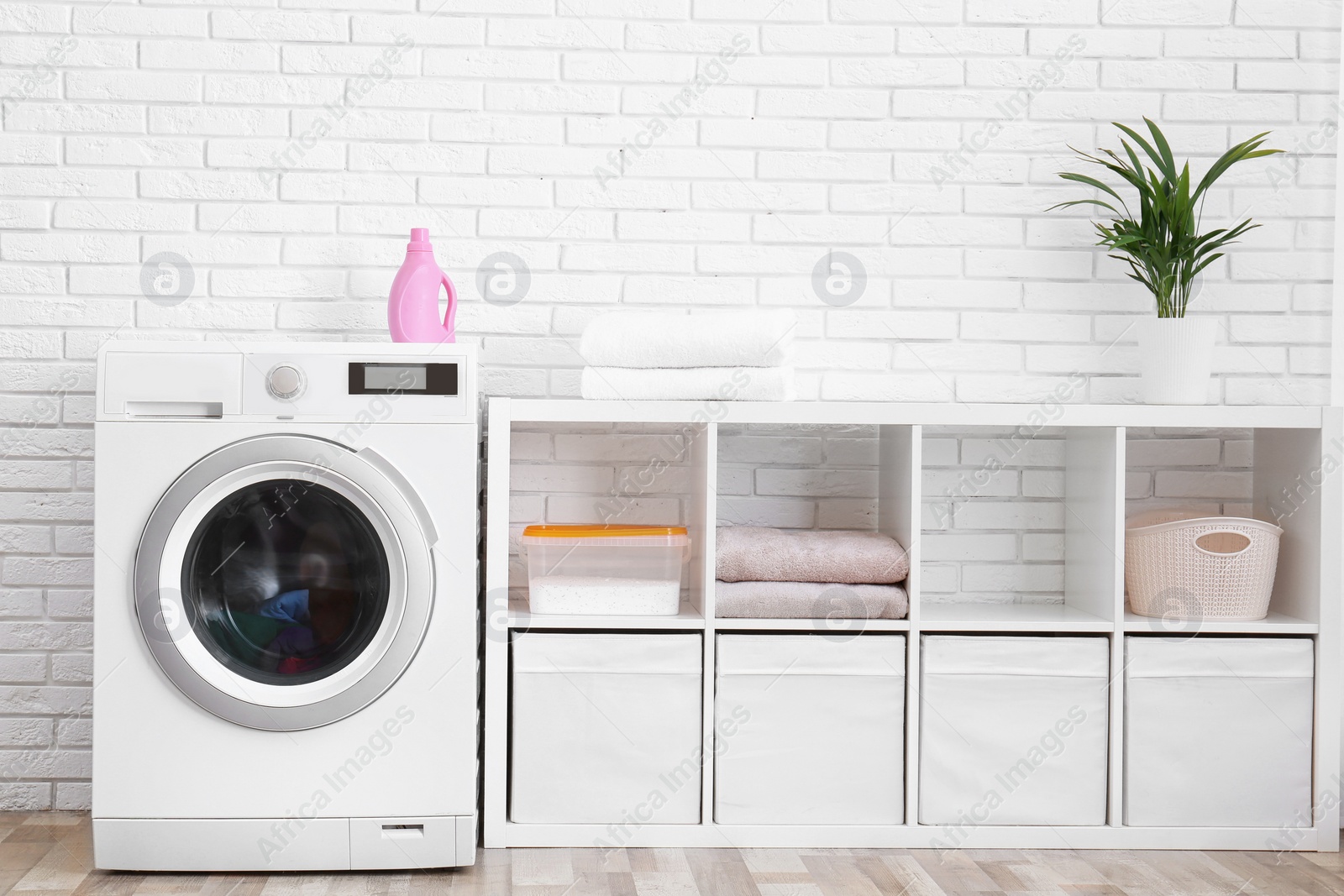 Photo of Modern washing machine near brick wall in laundry room interior