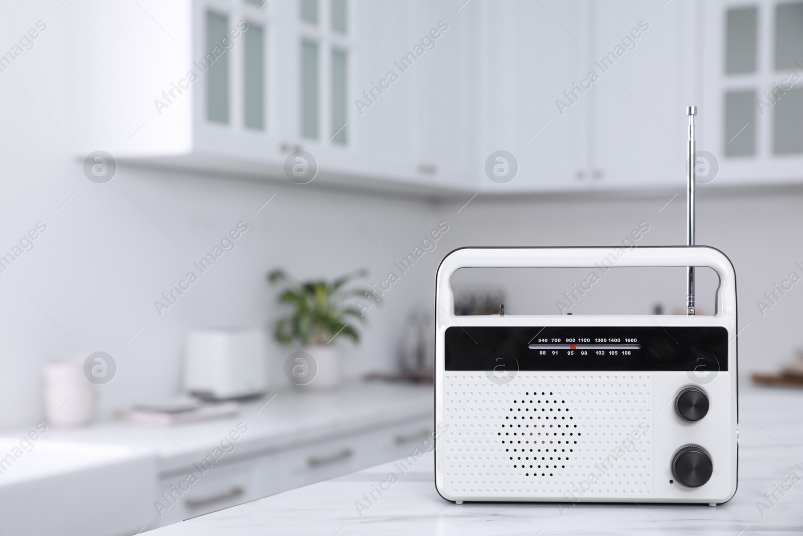 Photo of Stylish radio on white marble table in kitchen. Space for text