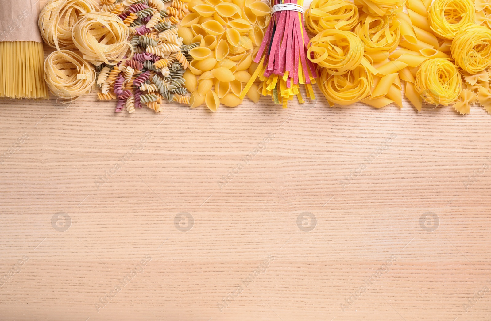 Photo of Different types of pasta on wooden table, flat lay. Space for text