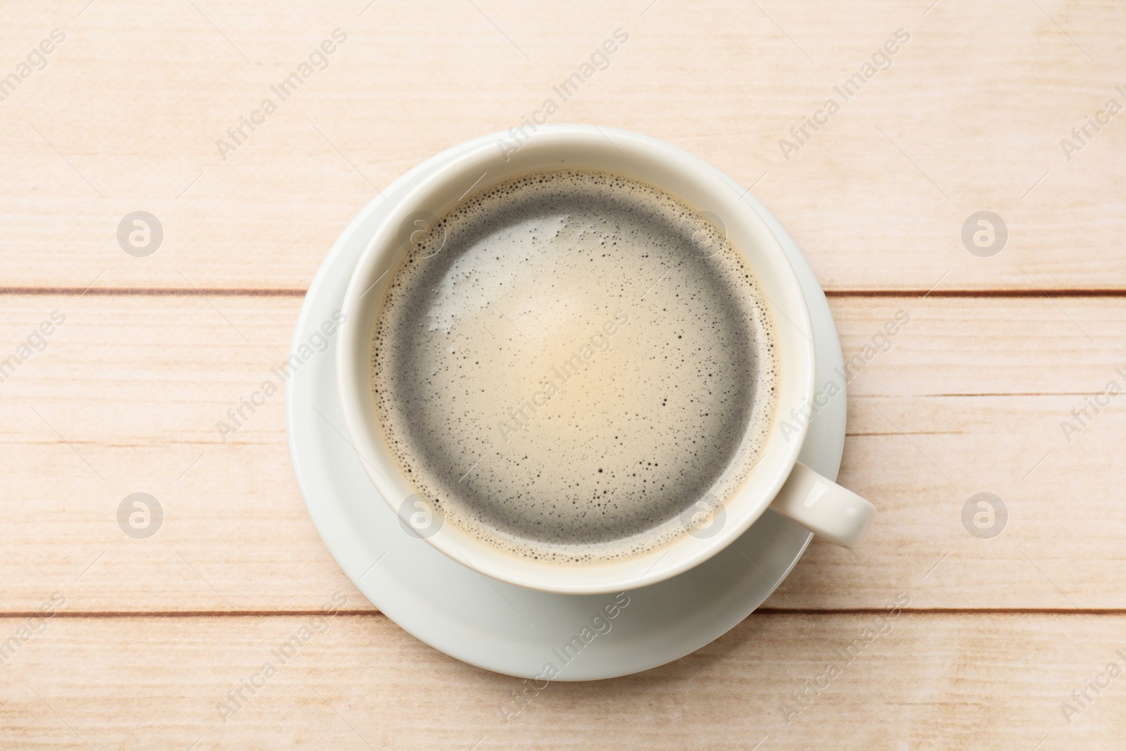 Photo of Cup of aromatic coffee on light wooden table, top view