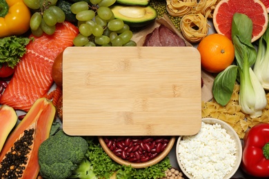 Photo of Wooden board among different products, top view with space for text. Healthy food and balanced diet