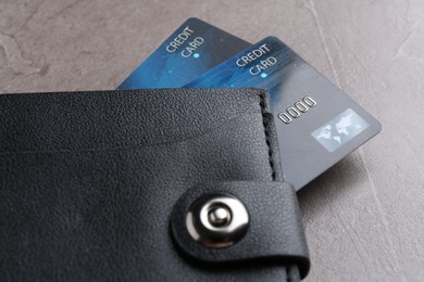 Photo of Credit cards in leather wallet on grey textured table, closeup