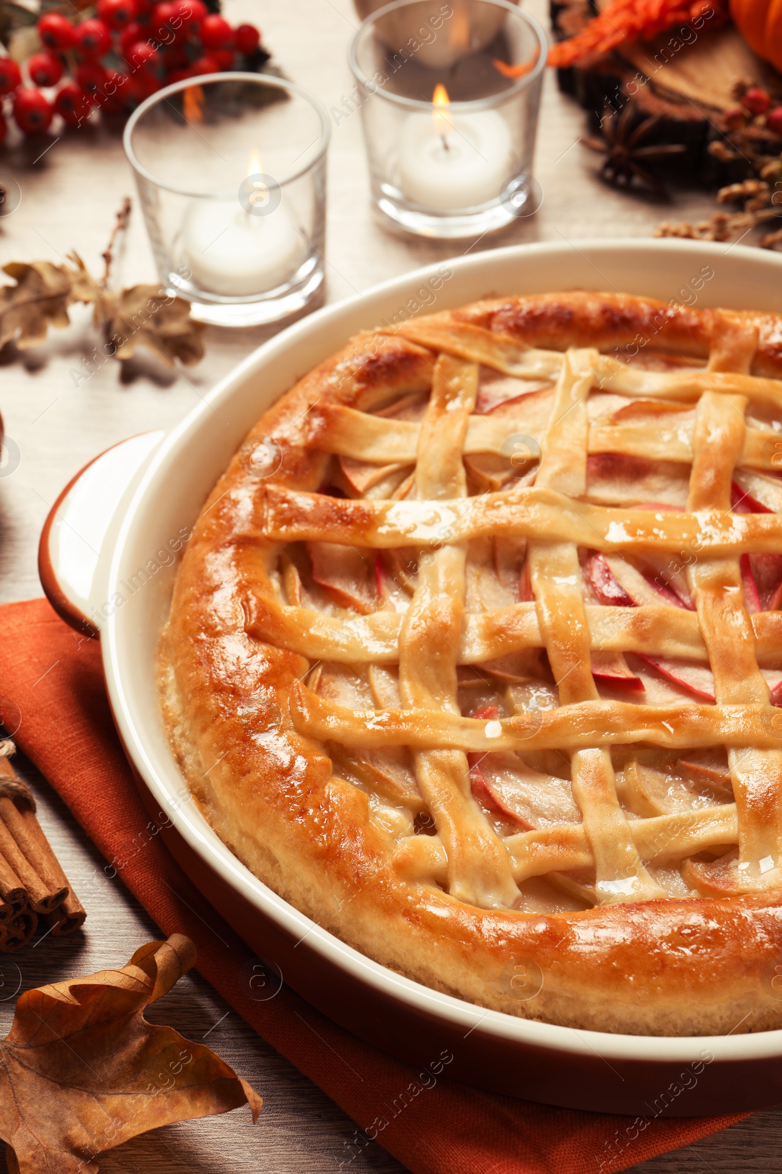 Photo of Delicious homemade apple pie and autumn decor on wooden table, closeup. Thanksgiving Day celebration