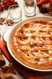 Photo of Delicious homemade apple pie and autumn decor on wooden table, closeup. Thanksgiving Day celebration
