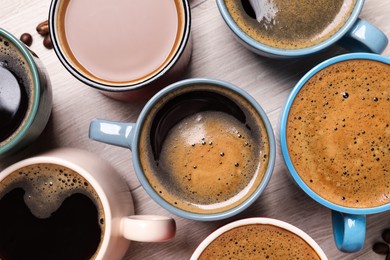 Photo of Many different cups of coffee on white wooden table, flat lay