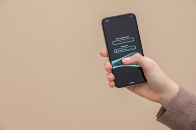 Photo of Woman unlocking smartphone with blocked screen on light brown background, closeup. Space for text