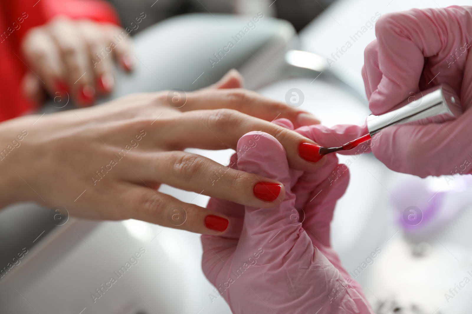 Photo of Professional manicurist applying polish on client's nails in beauty salon, closeup