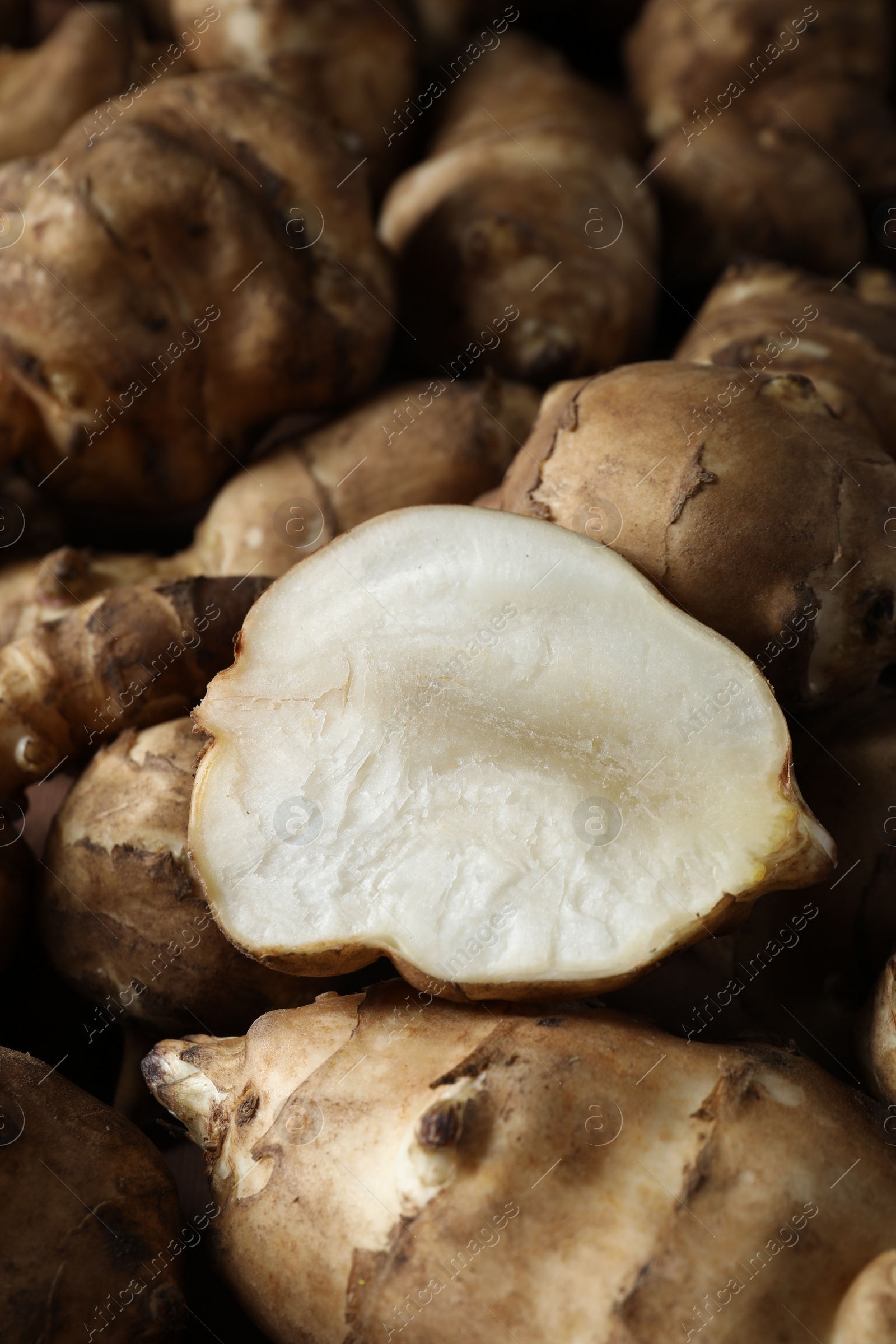 Photo of Whole and cut Jerusalem artichokes as background, closeup