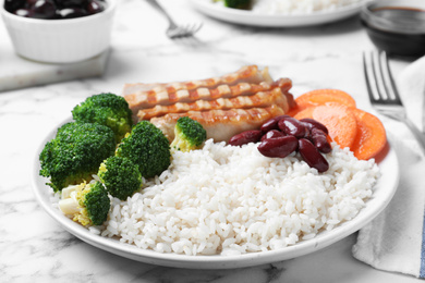 Photo of Delicious rice with beans and meat served on white marble table, closeup