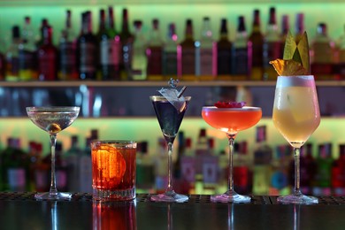 Photo of Different fresh alcoholic cocktails on counter in bar