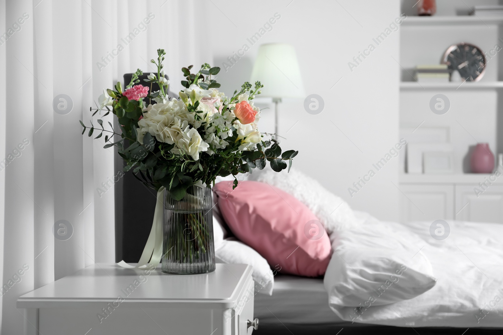 Photo of Bouquet of beautiful flowers on nightstand in bedroom