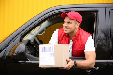 Photo of Courier giving parcel out of car window outdoors