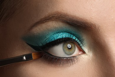 Photo of Applying eye shadow onto woman's face, closeup. Beautiful evening makeup