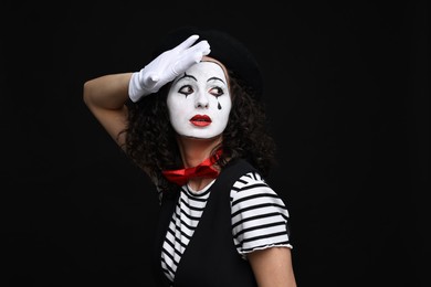 Young woman in mime costume posing on black background