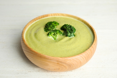 Photo of Delicious broccoli cream soup served on white wooden table