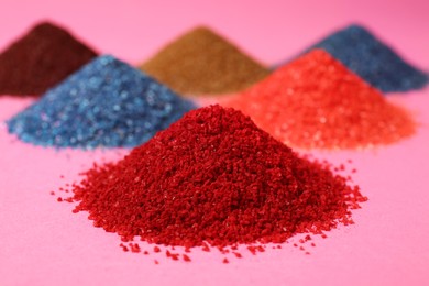 Heaps of different bright food coloring on pink background, closeup