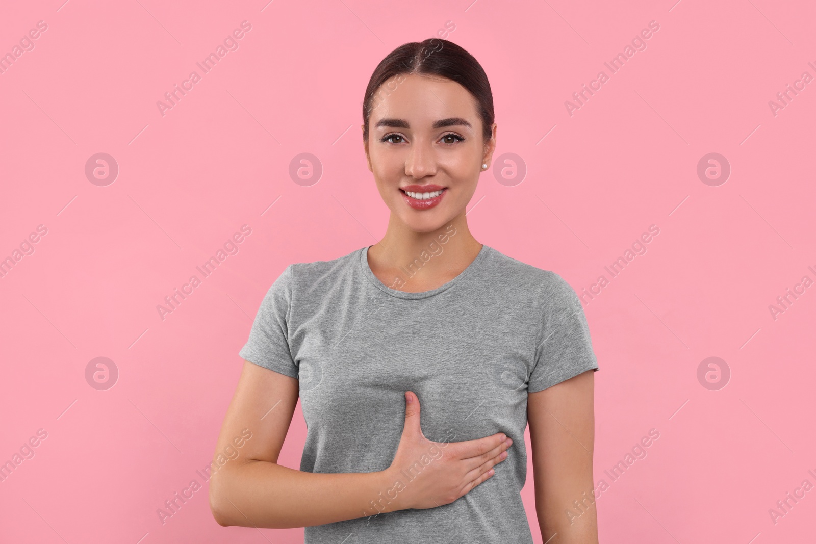 Photo of Beautiful young woman doing breast self-examination on pink background