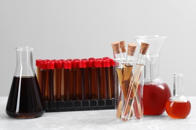 Photo of Different laboratory glassware with brown liquids on white table