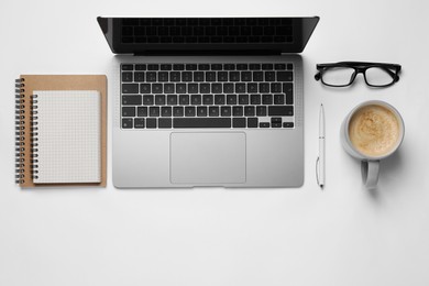 Photo of Modern laptop, notebooks, glasses and cup of coffee on white table, flat lay. Space for text