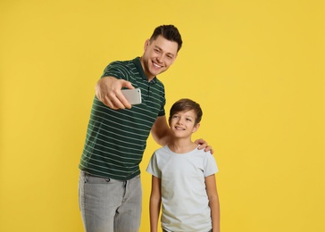 Dad and his son taking selfie on color background