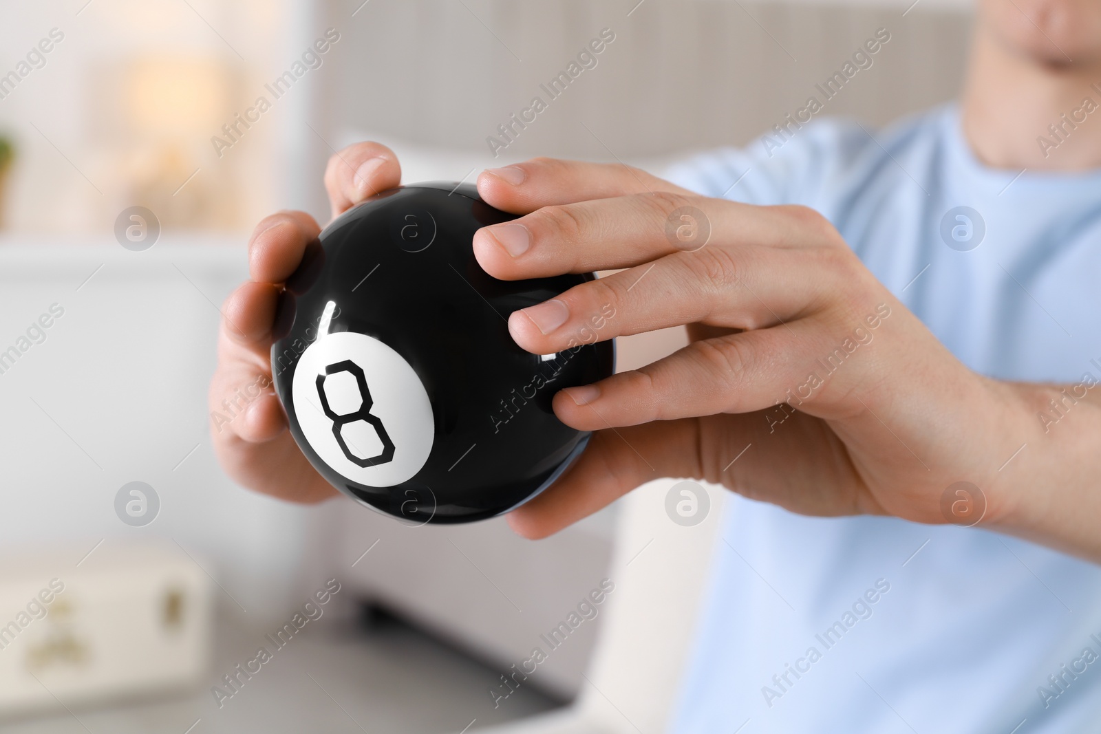 Photo of Man holding magic eight ball indoors, closeup