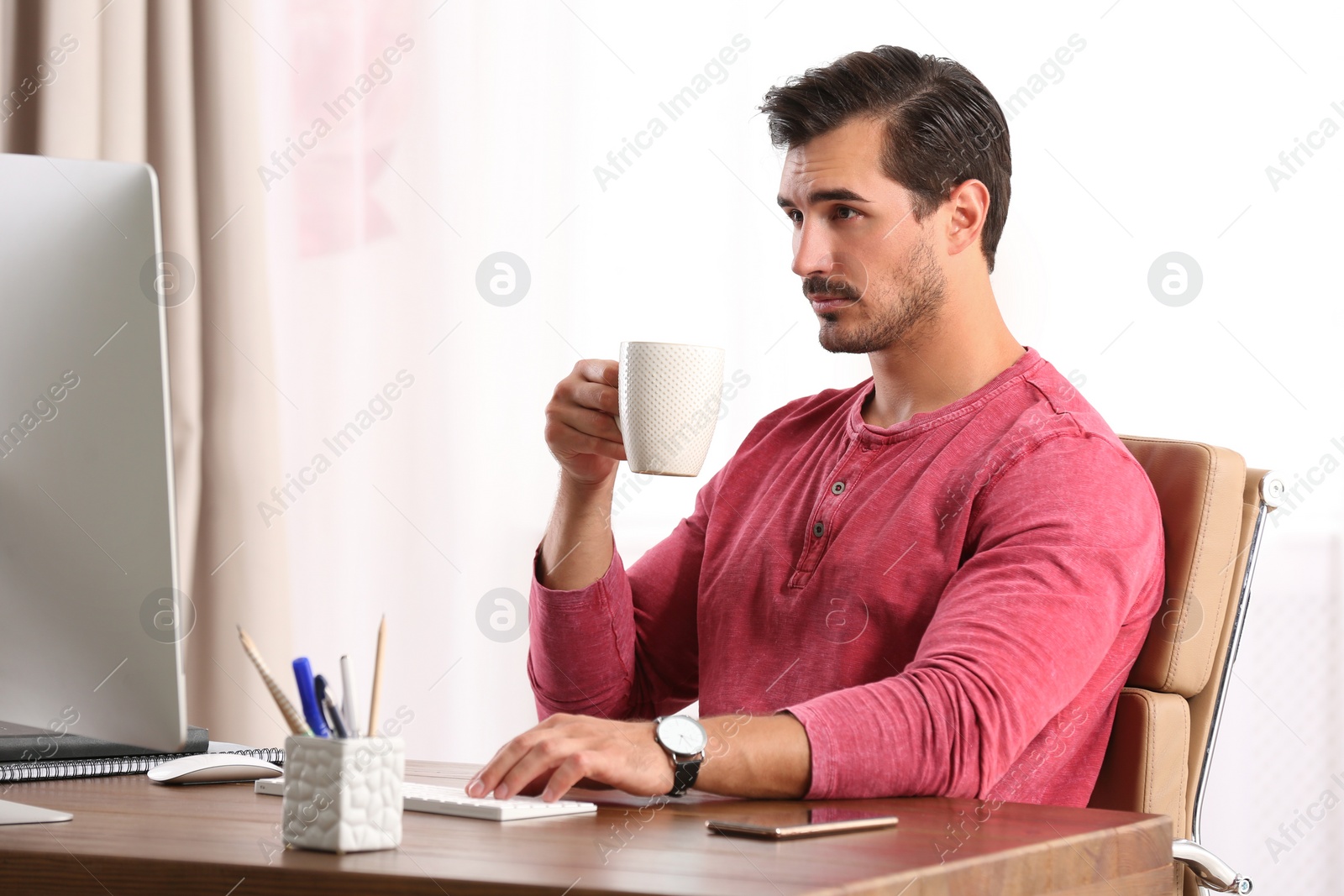 Photo of Handsome young man working with computer at table in office
