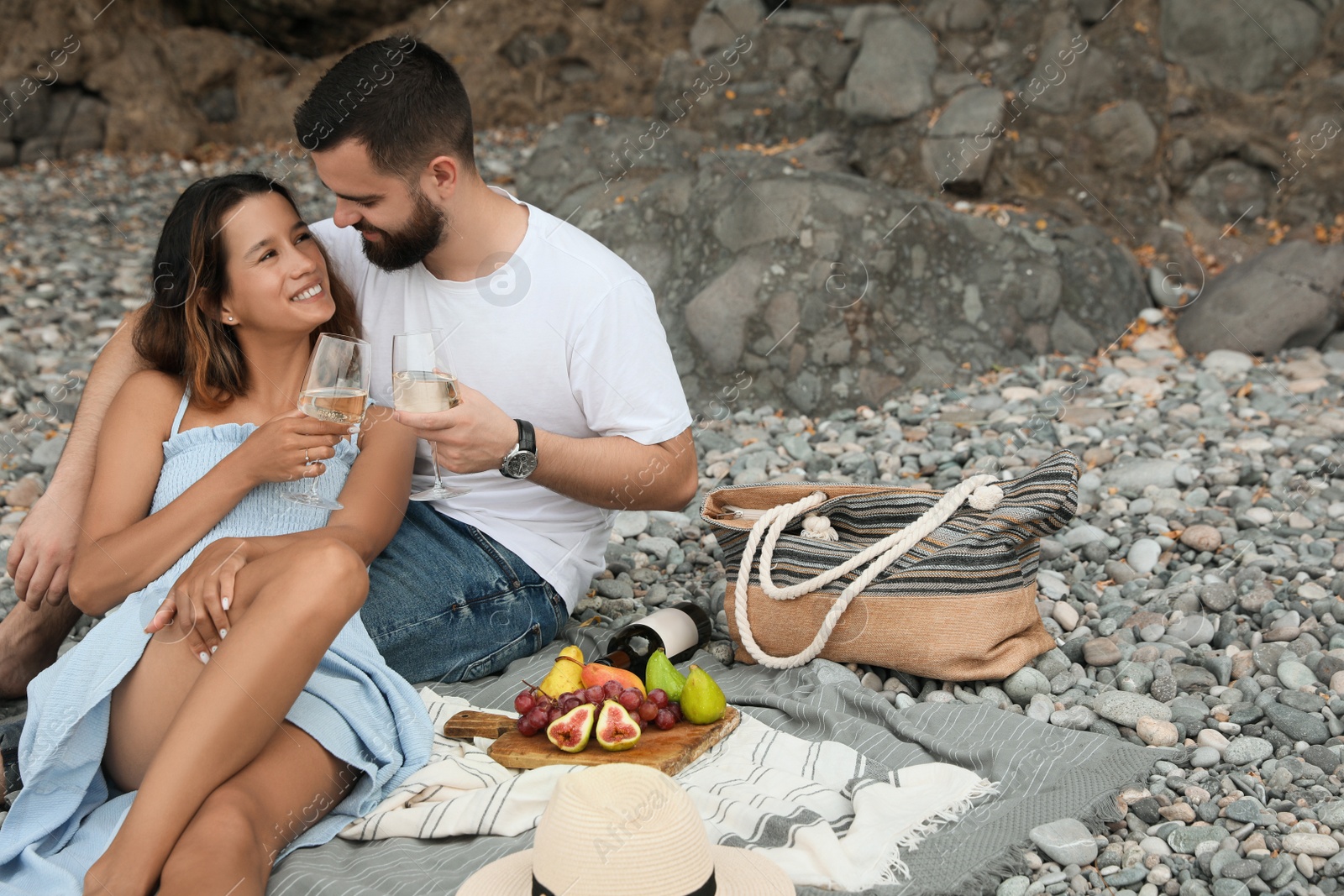 Photo of Happy young couple having picnic on beach. Space for text