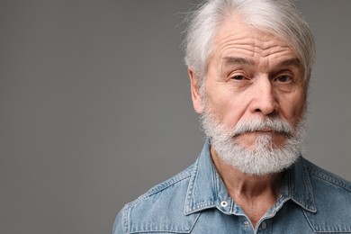 Senior man with mustache on grey background, space for text