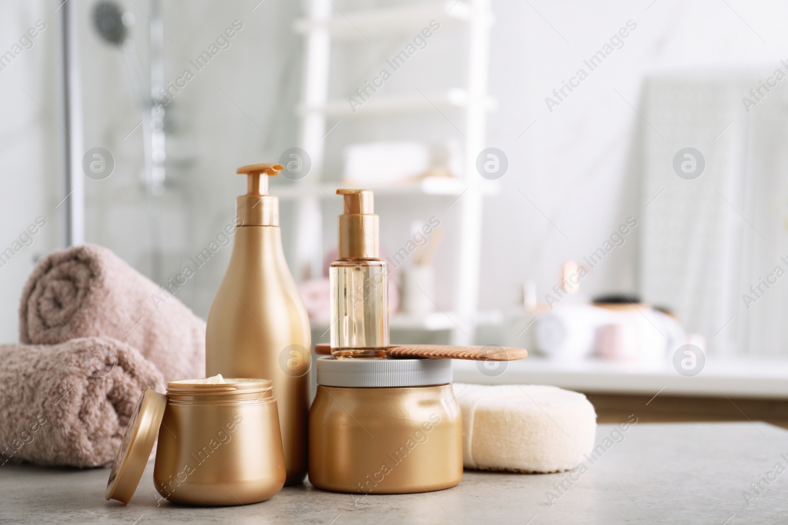 Photo of Different hair care products, towels and comb on table in bathroom