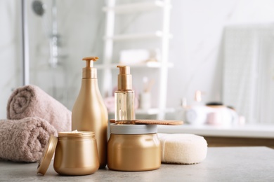 Different hair care products, towels and comb on table in bathroom