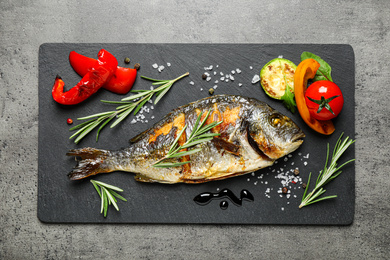 Delicious roasted fish and vegetables on grey table, flat lay