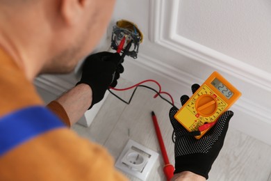 Electrician with tester checking voltage indoors, closeup