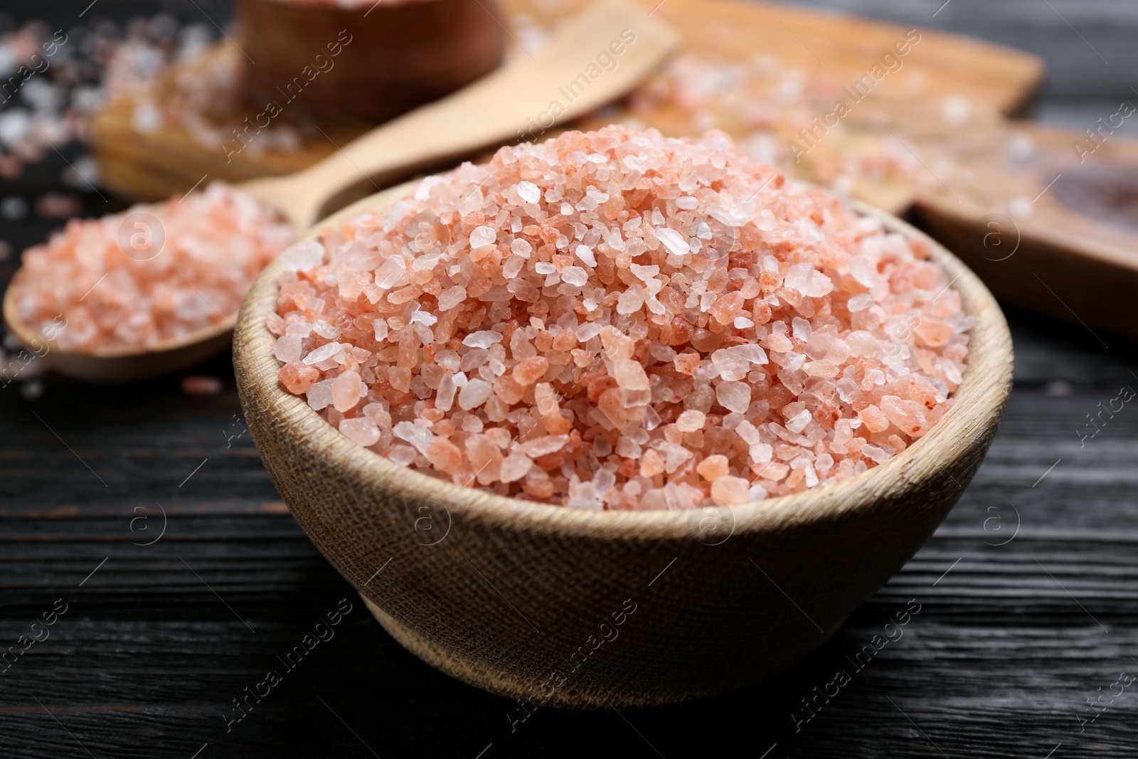 Photo of Pink himalayan salt in bowl on wooden table, closeup