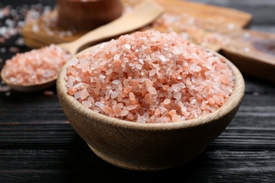 Photo of Pink himalayan salt in bowl on wooden table, closeup